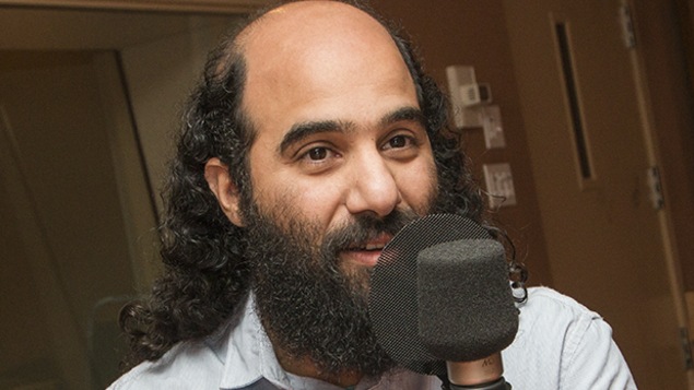 Un homme est photographié dans un studio de radio, devant un micro.