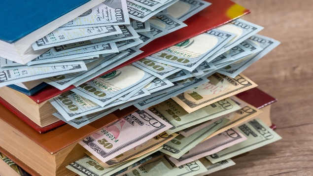Plusieurs billets américains glissés entre les pages de livres.