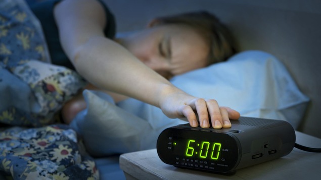 Une femme met la main sur son réveil-matin.