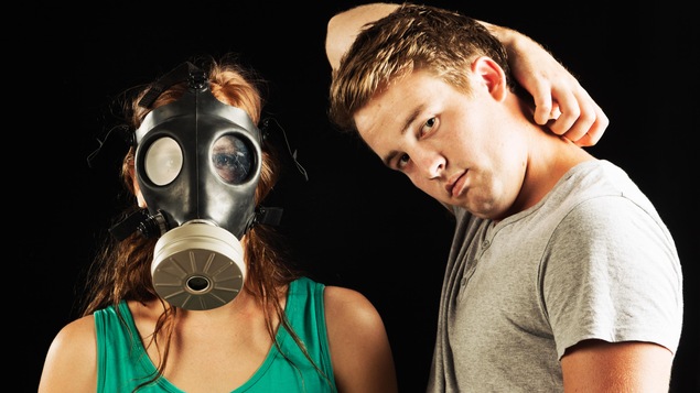Un homme sent fort des aisselles, et ce, en direction d'une femme portant un masque à gaz.