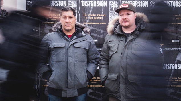 Sébastien Lévesque et Émile Gauthier debout devant un mur d'affiche