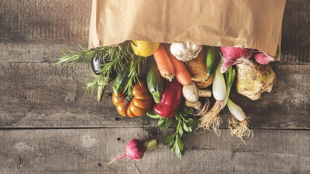 Des légumes frais sortant d'un sac renversé sur une table.