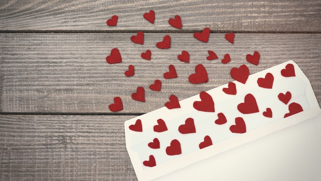 Des petits cœurs en papier rouge sortent d'une enveloppe blanche.