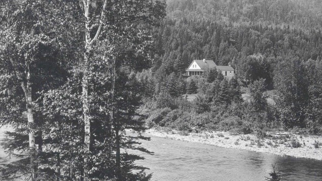 Photo en noir et blanc de 1910 où l'on voit le camp de pêche, photographié à partir de l'autre rive de la rivière Cascapédia