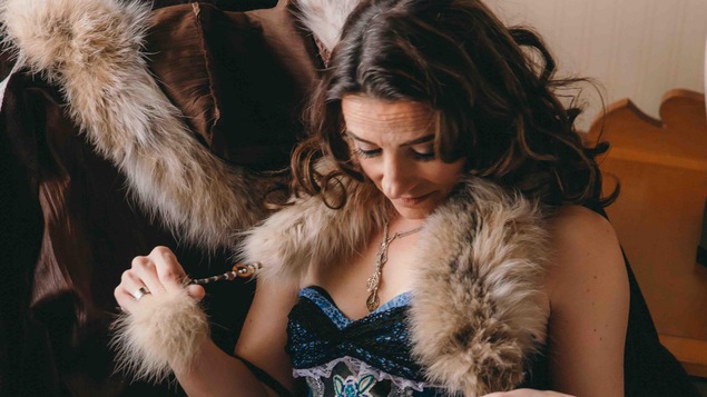 Une femme vêtue d'un deshabillé en denim, dentelle et fourrrure est assise sur une chaise.