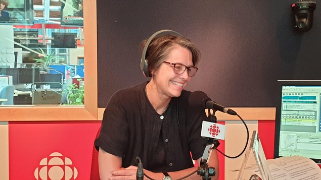 Une femme est assise devant un micro dans un studio de radio