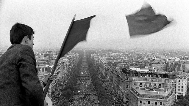 Un homme tient un drapeau français devant une foule de protestataires, lors de la manifestation 30 mai 1968 en soutien au président français Charles de Gaulle.