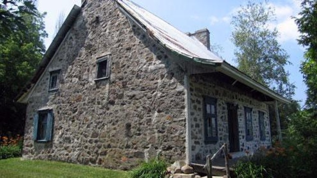 Une maison ancestrale en pierres avec du gazon vert.