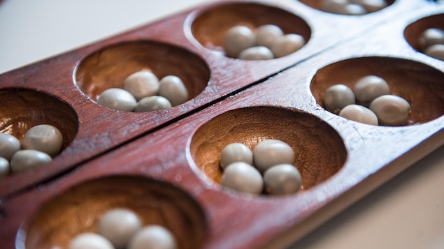 Deux planches où l'on a creusé des petites cavités où sont déposées des cailloux.