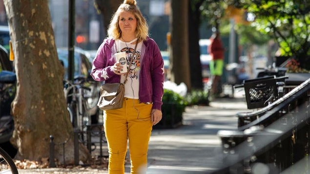 Une femme tient un café sur le trottoir de la rue.
