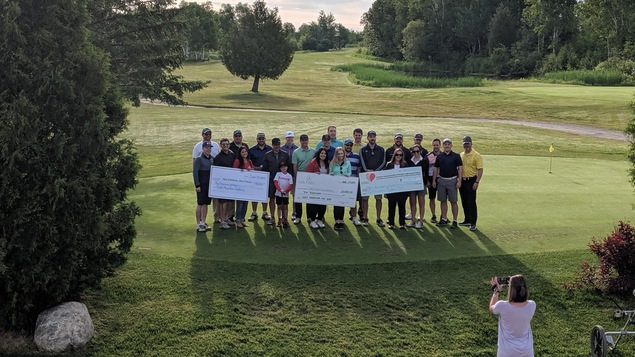 24 golfeurs sur un terrain de golf à Sudbury. Une dame prend leur photo.