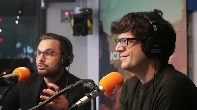 Deux jeunes hommes mènent une discussion animée au micro, l'un d'eux sourit.
