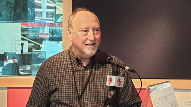 Un homme est assis devant un mirco dans un studio de radio.