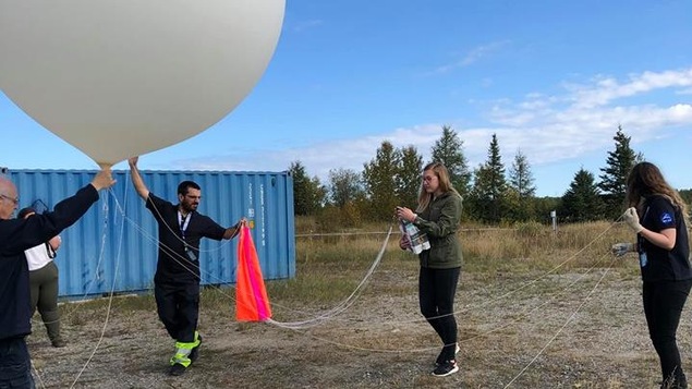 Quatre personnes manipulent un ballon stratosphérique