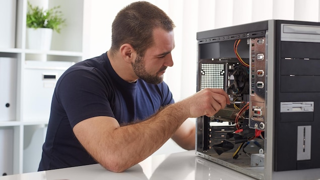 Un homme répare le disque dur de son ordinateur.