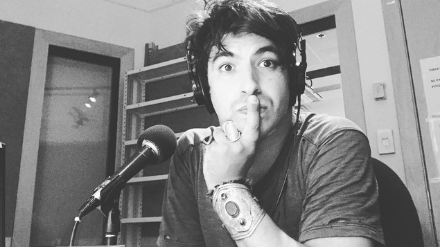 Un homme est dans un studio de radio et regarde la caméra.