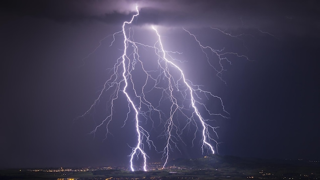 Des éclairs déchirent le ciel au-dessus d'une ville.