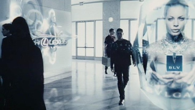 Un homme marche dans une foule d’hologrammes.