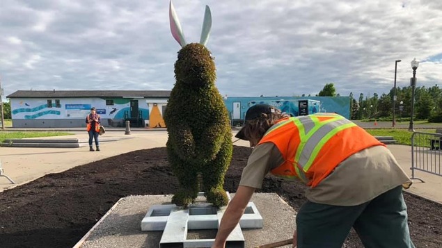Un horticulteur devant une sculpture végétale représentant un lapin géant
