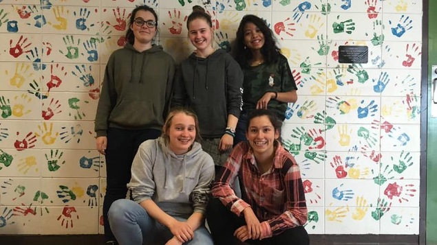 Cinq étudiantes posent devant le mur de la classe