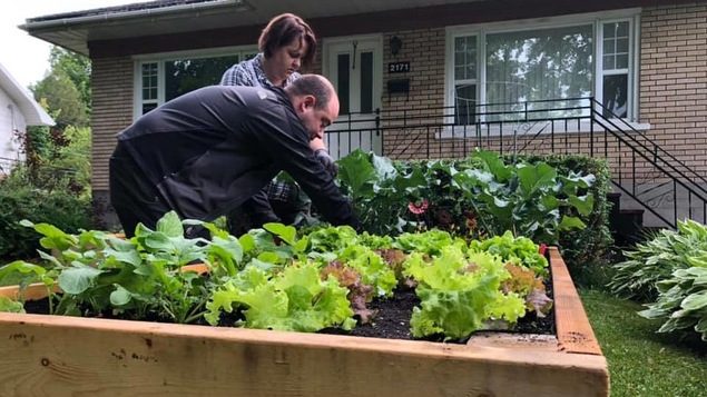 Un couple travaille à l’aménagement d’un potager en façade de leur maison