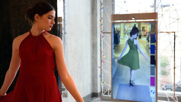 Une femme porte une robe rouge et son reflet dans le miroir porte une robe verte.