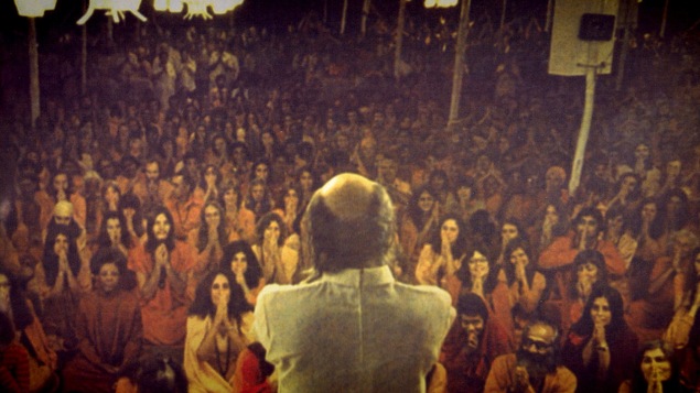 Une scène montre Bhagwan Rajneesh devant des disciples dans le documentaire <em>Wild Wild Country</em>.