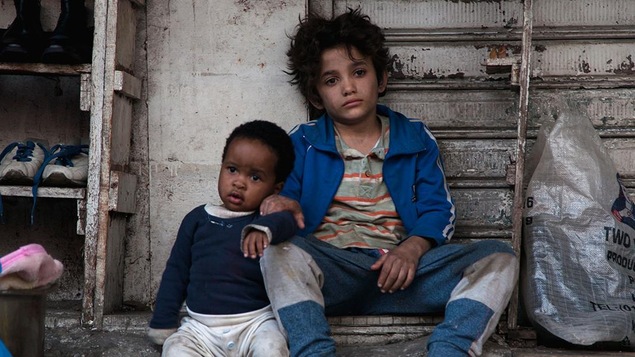 Boluwatife Treasure Bankole et Zain Al Rafeea regardent au loin, assis sur le sol contre un mur, dans cette image tirée du film <i>Capharnaüm</i>, de Nadine Labaki.