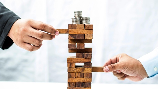 Deux mains déplacent des blocs sur un puzzle en forme de tour. Des pièces de monnaie se trouvent sur le dessus du puzzle.