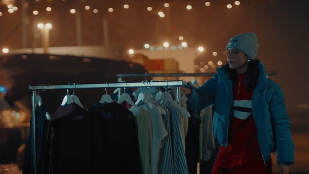 Une femme place des vêtements sur un présentoir en bordure de la route sur cette image tirée d'une publicité de l'organisme Fashion Revolution.
