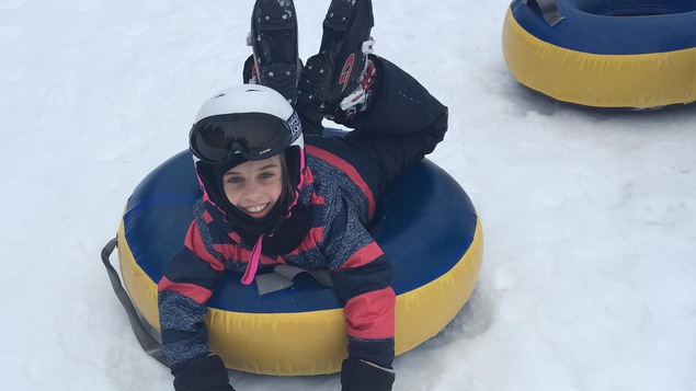 Une jeune fille sur un tube pour glisser sourit à la caméra.