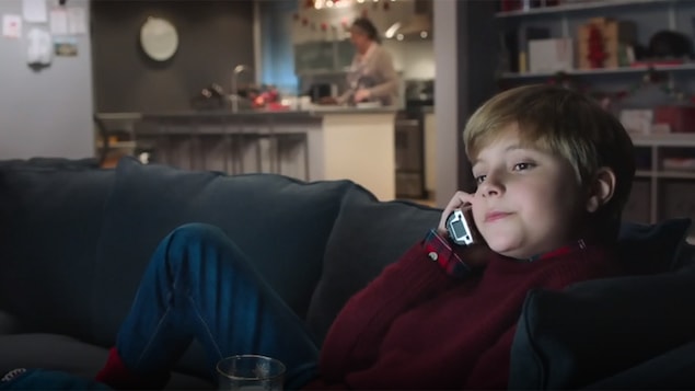 Un enfant assis sur un canapé discute au téléphone dans cette image tirée d'une publicité des Producteurs de lait du Québec.