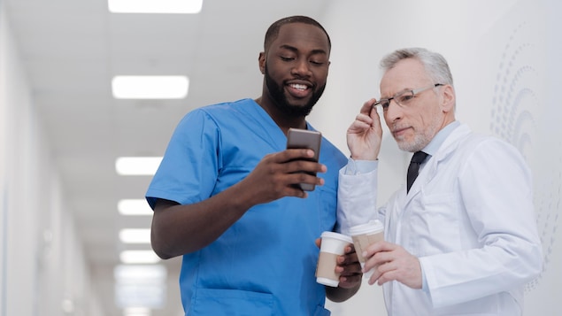 Un jeune homme montre à un homme plus âgé quelque chose sur son téléphone intelligent.