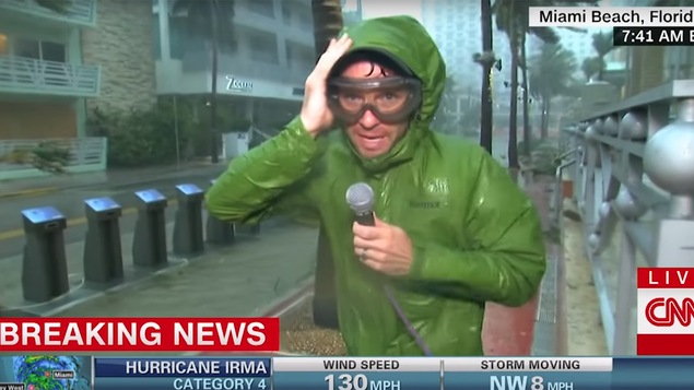Un journaliste parle à la caméra en tenant son capuchon, à la pluie battante, durant l'ouragan Irma de 2017.