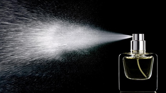 Du parfum vaporisé jaillissant d'une bouteille.