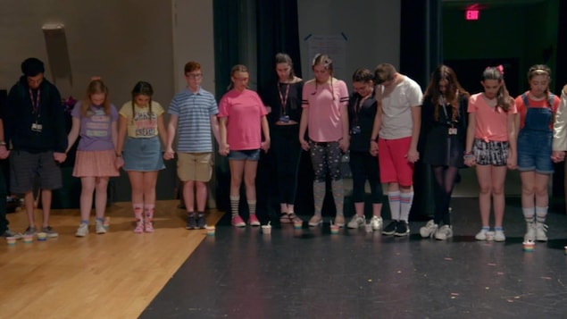 Des adolescents se tiennent la main, les yeux fermés et la tête penchée en recueillement, sur cette image tirée du documentaire <i>Song of Parkland</i>.