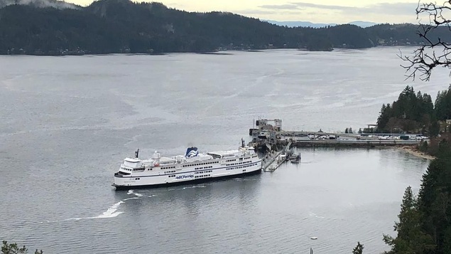 Un bateau près d'un grand quai, les montagnes en arrière-plan.