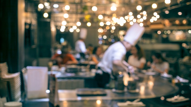 Scène floutée montrant des cuisiniers dans une cuisine de restaurant.