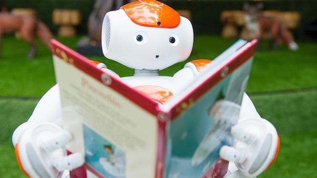 Un robot à l'allure sympathique tient un livre et fait mine de lire.