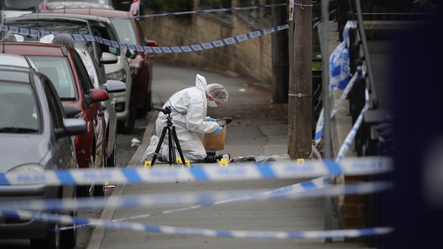 Un médecin légtiste se penche sur un cadavre à Birstall, en Angleterre.