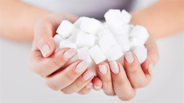 Une femme tient des cubes de sucre dans ses mains.