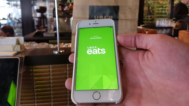 Une main tenant une téléphone cellulaire qui affiche l'application Uber Eats.