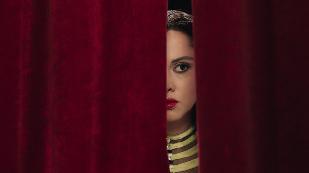Yasmin Raeis regarde entre deux pans de rideaux dans cette image tirée du film <i>Looking for Oum Kulthum</i>, de Shirin Neshat.