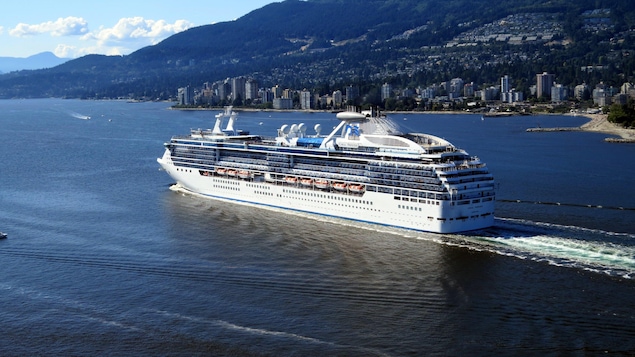 Une navire de croisière navigue dans les eaux d'une ville.