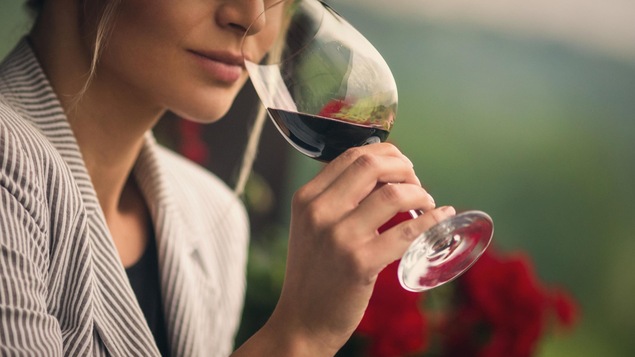 Une femme d'apprête à goûter à un vin rouge.