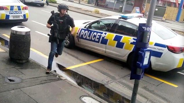Un policier court avec une arme longue à la main.