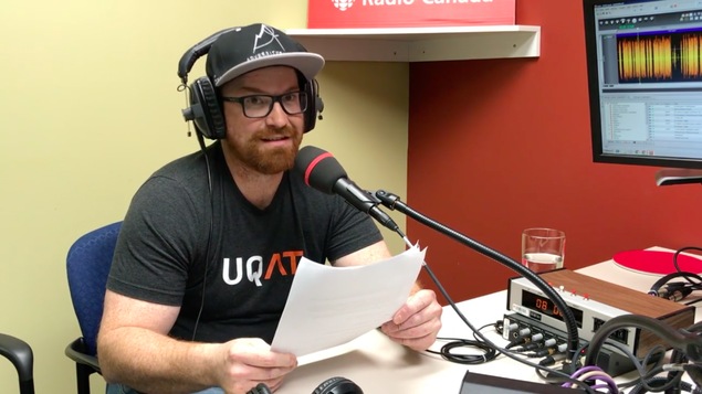 Un homme portant des lunettes et une casquette parle au micro dans nos studios de Val-d'Or.