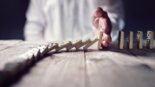 Une main retient une dégringolade de dominos