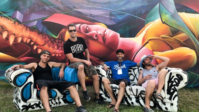 Quatre membres du ASHOP CREW assis sur des divans devant leur murale aux Wynwood Walls à Miami.