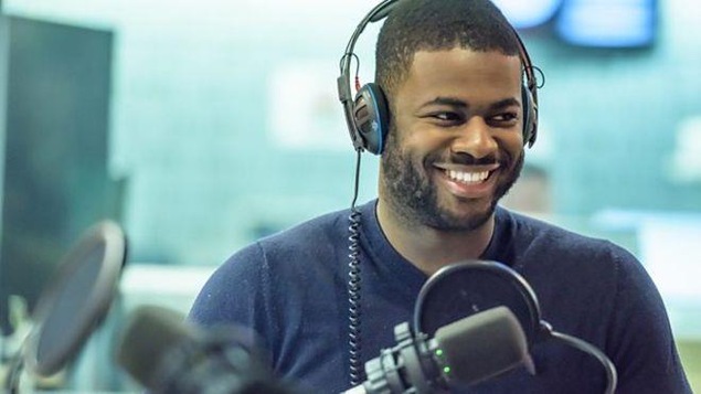 Ben Hunte, souriant, avec des écouteurs, devant un micro.